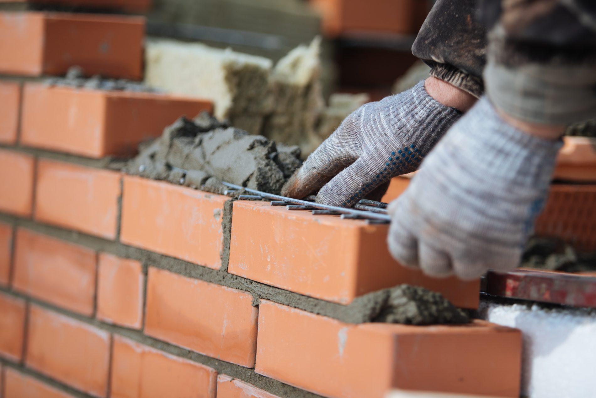 Mason applying mortar between red bricks during construction work