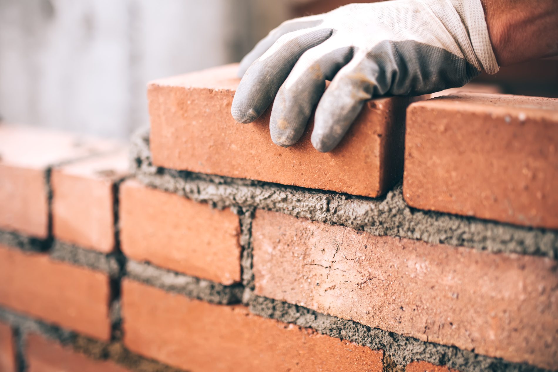 Mason placing brick on mortar bed during construction